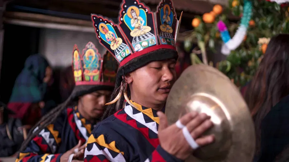 Gurung dancer in a painted festival crown playing cymbals