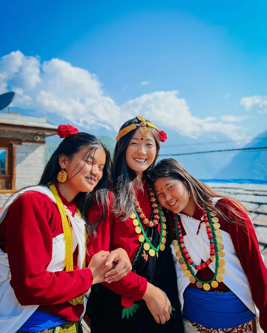 Three young Gurung women in traditional dress and jewellery