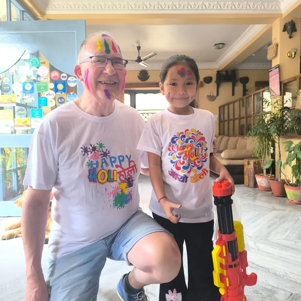 A guest and a young girl covered in Holi colours