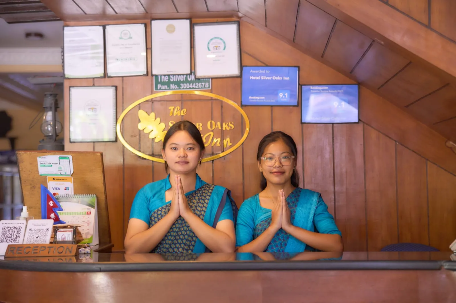 Two receptionists greeting with namaste at The Silver Oaks Inn front desk